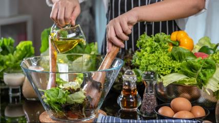 Čovek sipa ulje u činiju sa listovima zelene salate