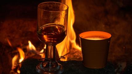 Kuvana rakija u čaši pored vatre