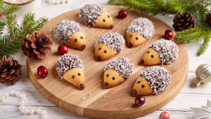 Ježići sa čokoladom i kokosom na dasci okruženi novogodišnjom dekoracijom