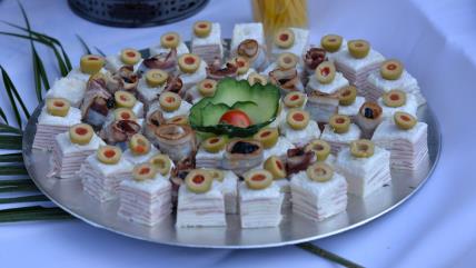 Slana oblanda sa sirom i šunkom isečena na kockice, ukrašenim maslinama i poslagana na srebrnom tanjiru