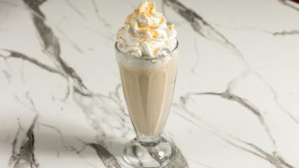 Plazma šejk u staklenoj čaši sa šlagom i posut mlevenom plazmom