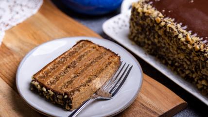 Parče Reforma torte na belom tanjiru sa viljuškom na stolu