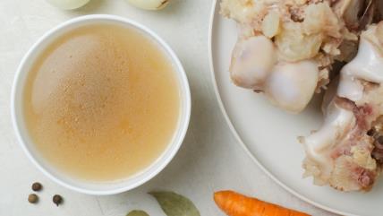 Supa od kostiju u činiji pored tanjira sa kostima