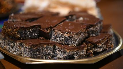 Posni kolač sa makom preliven čokoladom na metalnom tanjiru