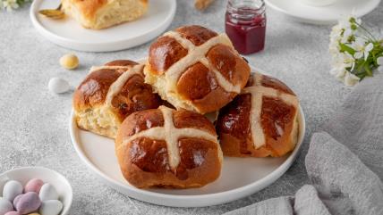 Uskršnje slatke zemičke sa suvim grožđem na belom tanjiru