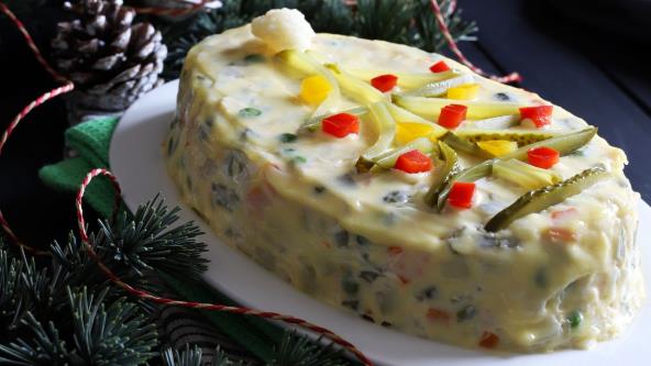 Rumunska salata na poslužavniku ukrašena turšijom i okružena šišarkom i borovim iglicama