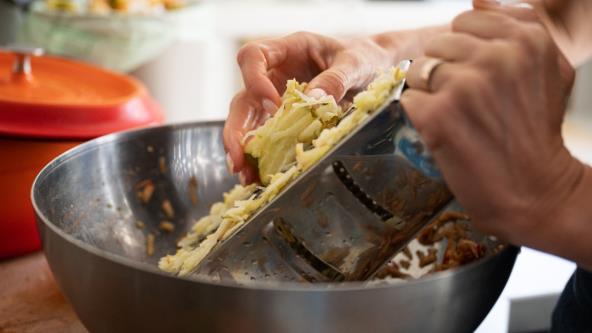 Žena renda jabuke u činiju